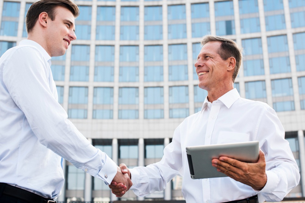 Handshake between two men outside building signifies agreement for offshore company setup in Dubai.